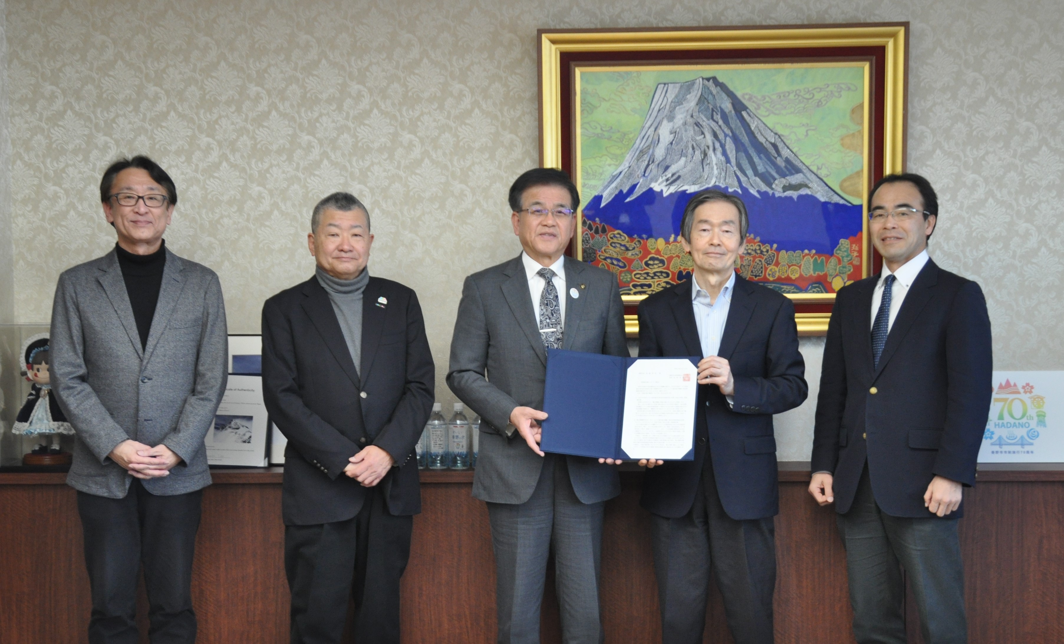 市長（中央）に報告書を手渡す坂野会長（右から2人目）と委員（令和7年2月12日市長報告会にて） 